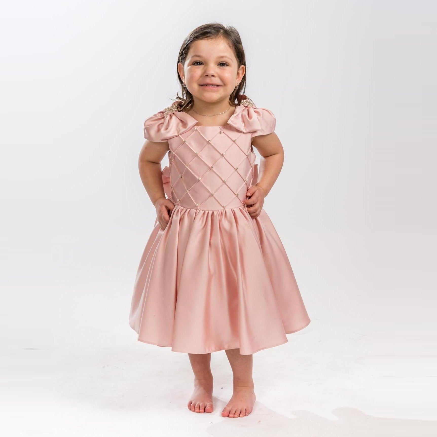 Young girl wearing a pink dress with puffed sleeves on a white background