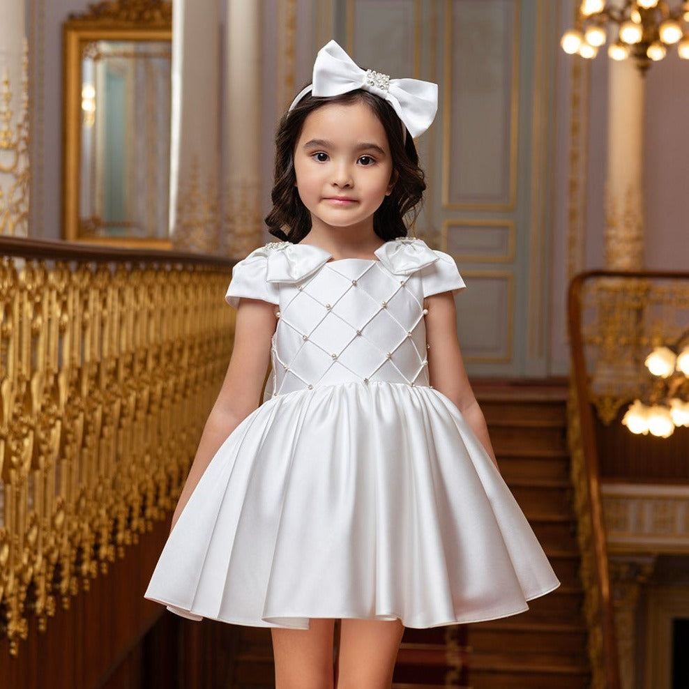 Young girl in a white dress with a bow in an elegant interior setting