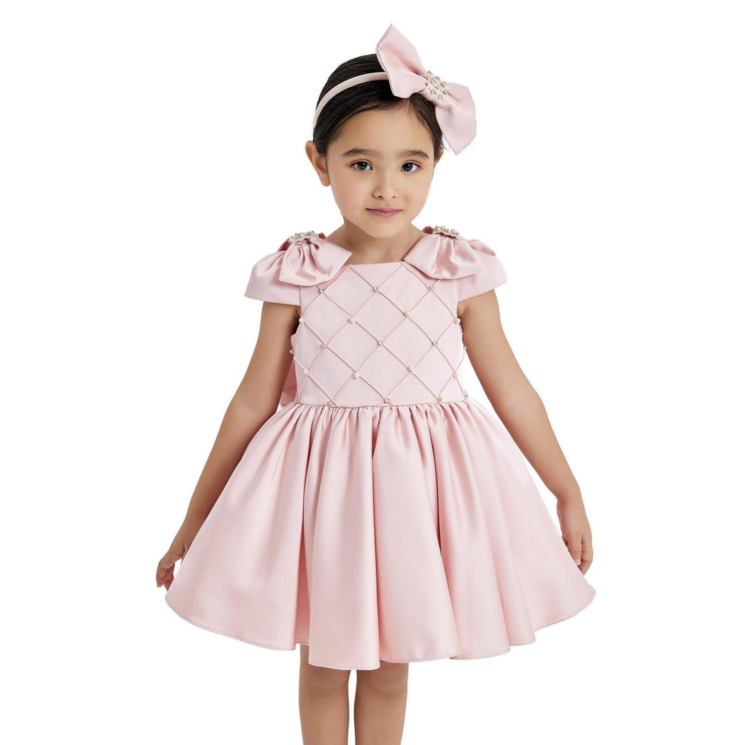 Young girl wearing a pink dress with ruffled sleeves on a white background